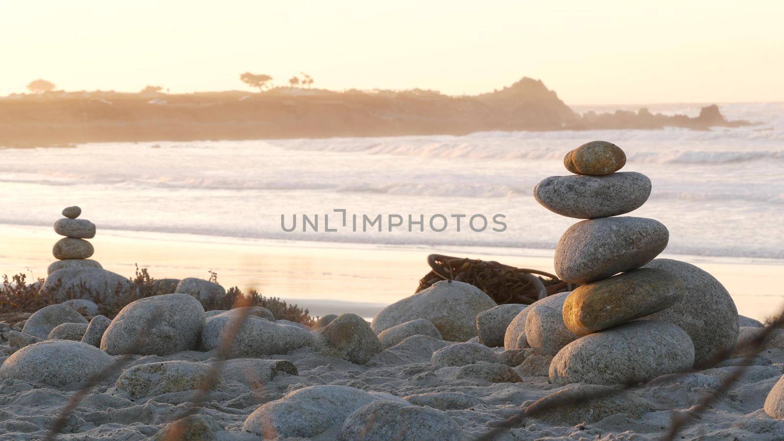 Rock balancing on pebble beach. Pyramid stacks of stones, ocean coast, sea water by DogoraSun