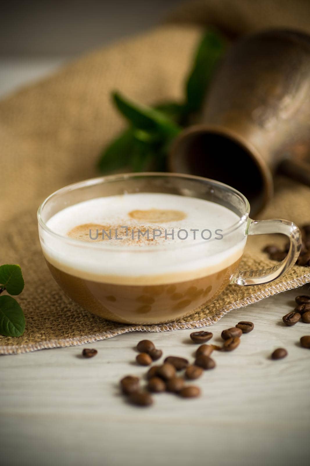 Cup of coffee latte with heart shape and coffee beans on old wooden background