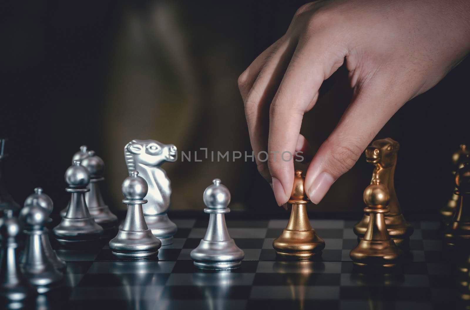 Hand businessman moving silver pawn chess fighting on board with gold chess background. successfully in the competition with technology network background. Management or leadership strategy concept.