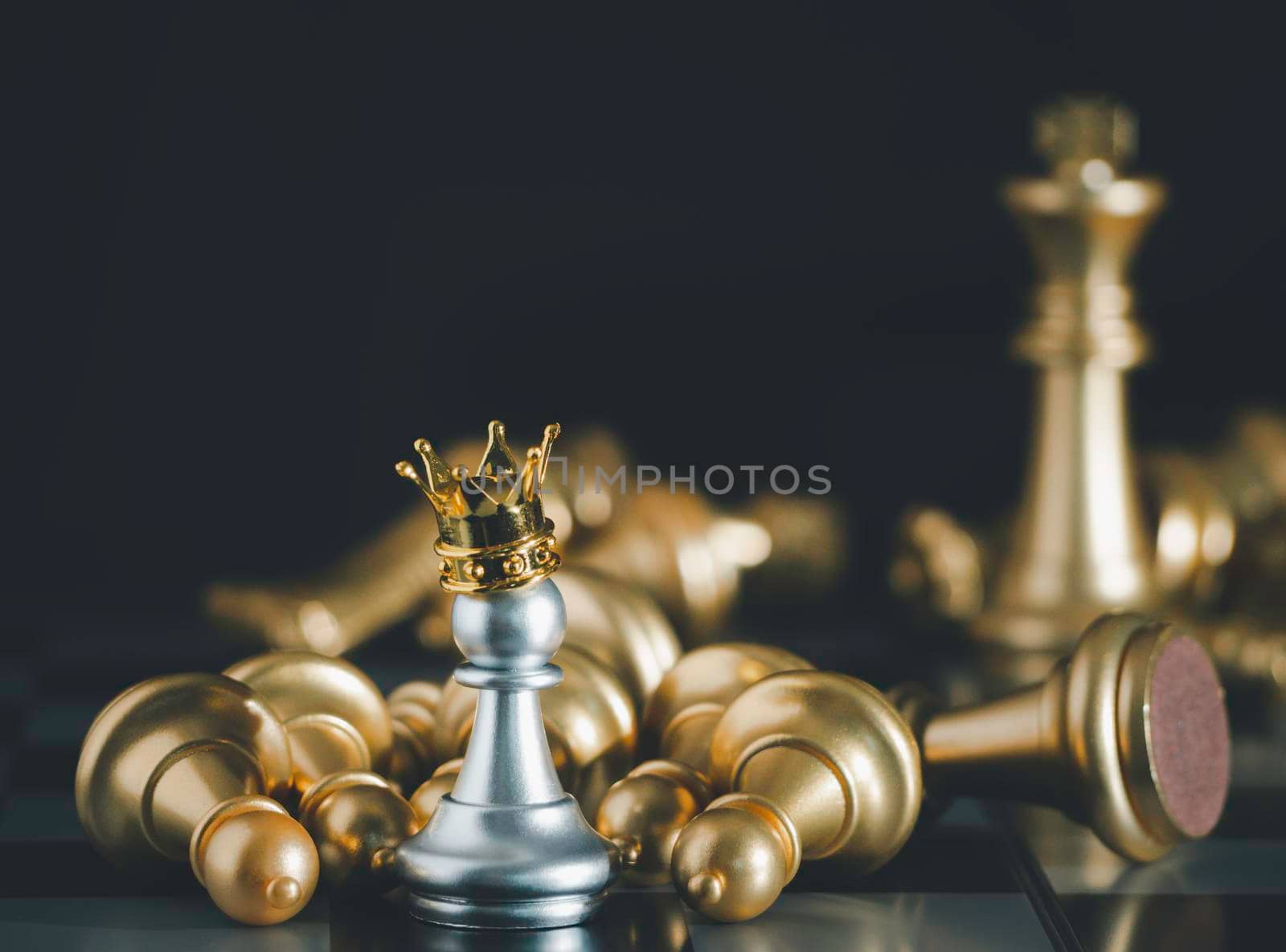 A silver pawn standing crowned in battle chess game on board with gold chess background. To fighting with teamwork to victory, business strategy concept and leader and teamwork concept for success.