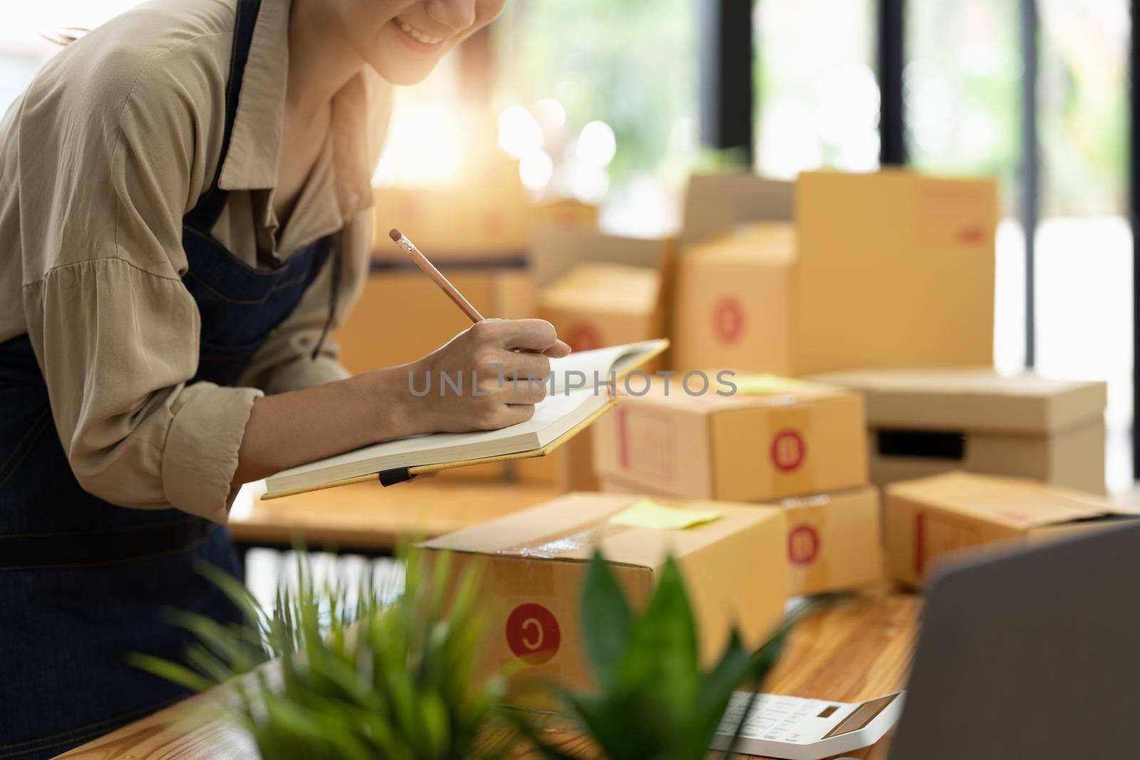 Startup SME small business entrepreneur SME or freelance Asian woman using a laptop with box, online marketing packaging box and delivery, SME concept.