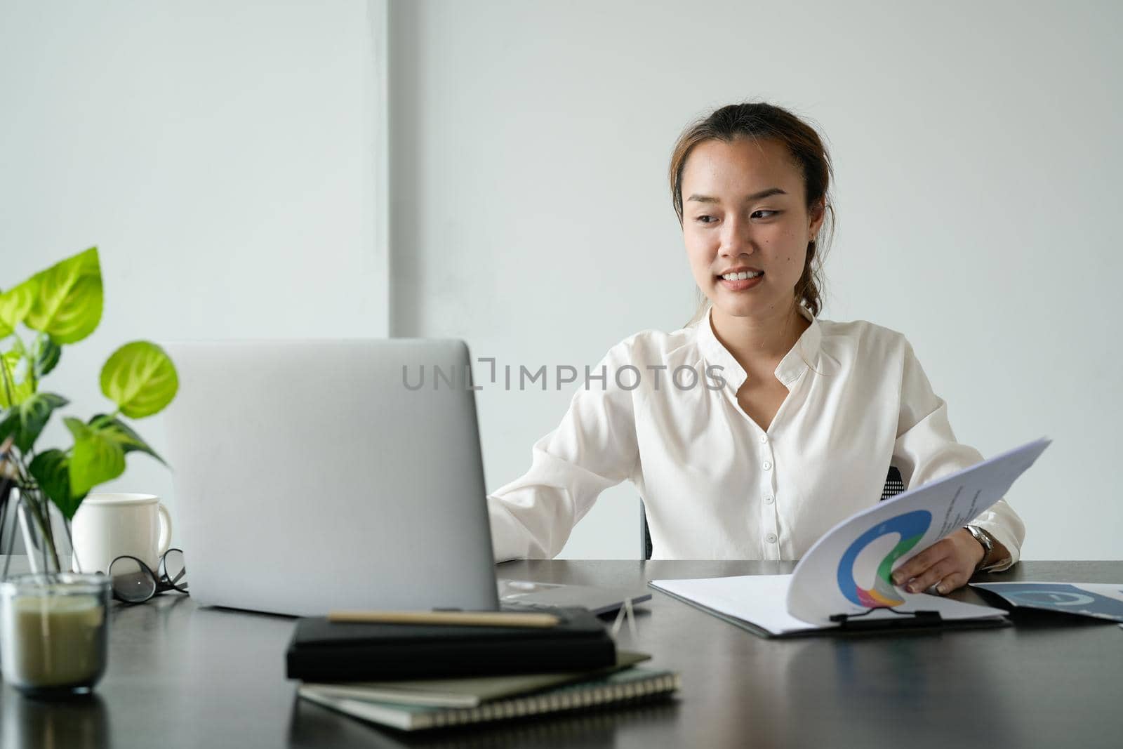 Young asian businesswoman sitting on her workplace in the office. Young woman working at laptop in the office.