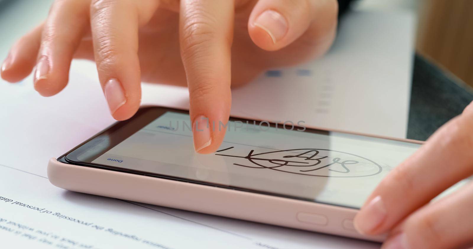 Electronic Signature on smartphone screen with woman hand. Sign Document of Deal at Work in Office Indoors. Write Business Agreement for Entrepreneur. Contract digital signature.