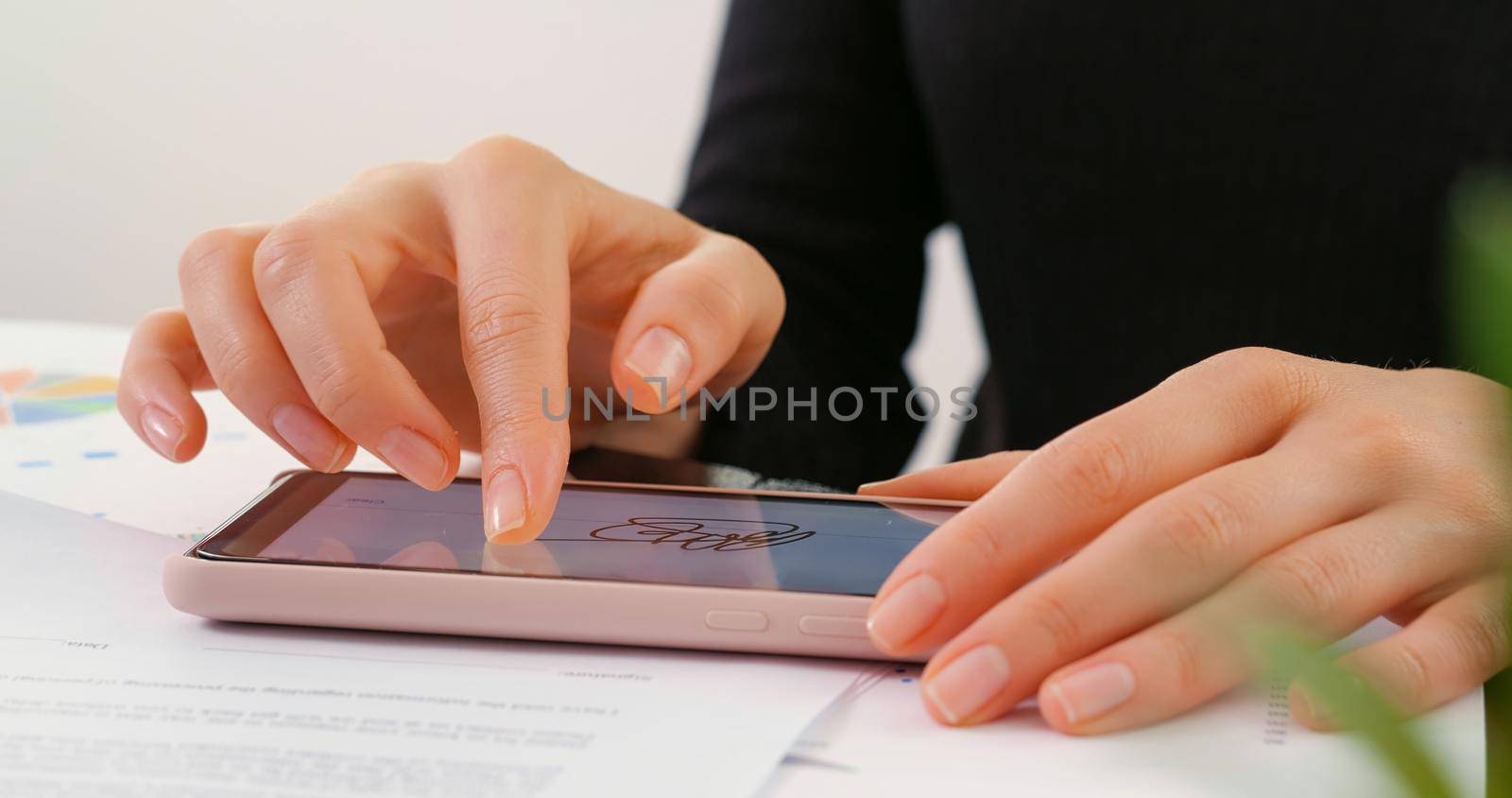 Digital signature on phone. Bussines woman signs on the smartphone screen electronic signature concept. E-signing. Female hand signing digital contract on lighted smartphone screen with finger.