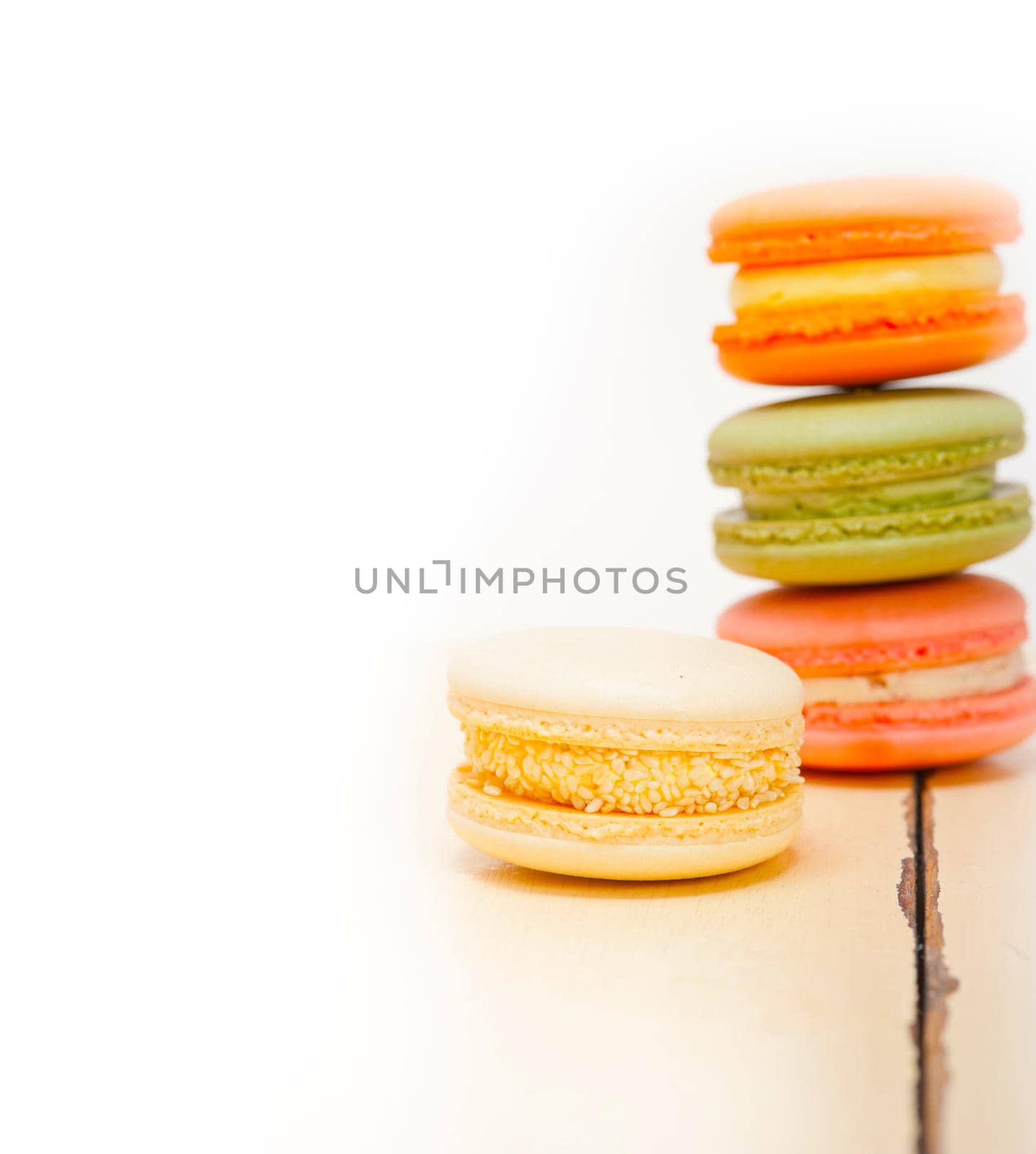 colorful french macaroons over a white rustic wood table 