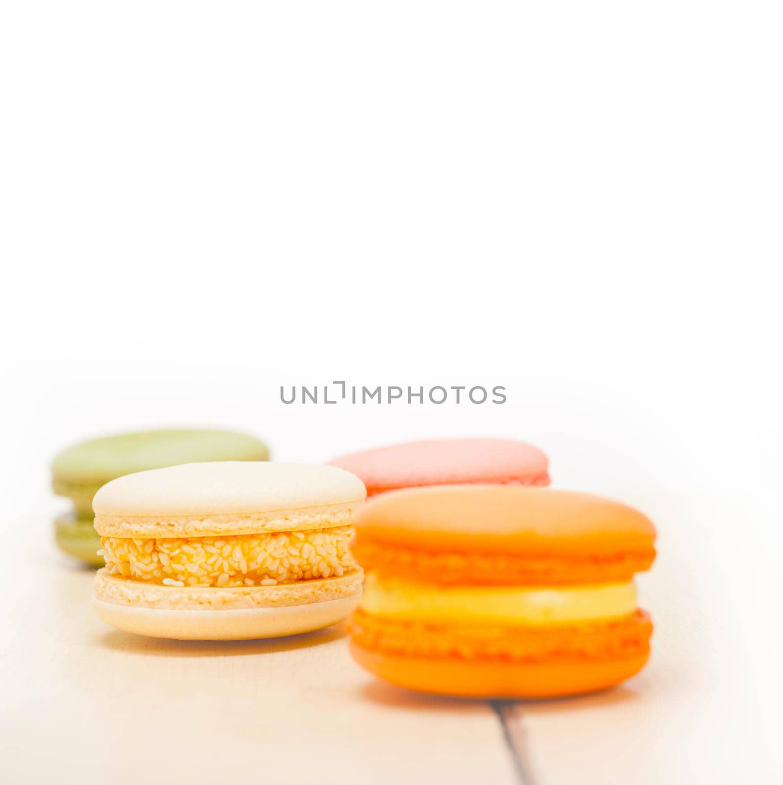 colorful french macaroons over a white rustic wood table 