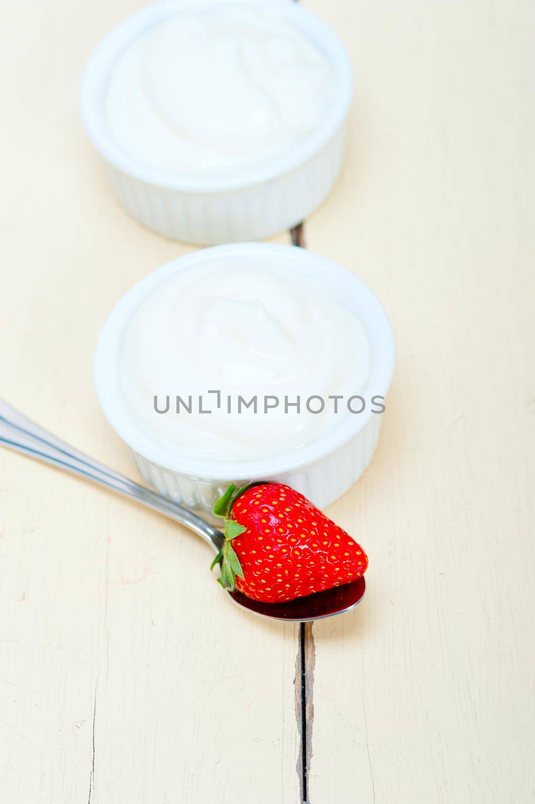 organic Greek yogurt and strawberry over white rustic wood table