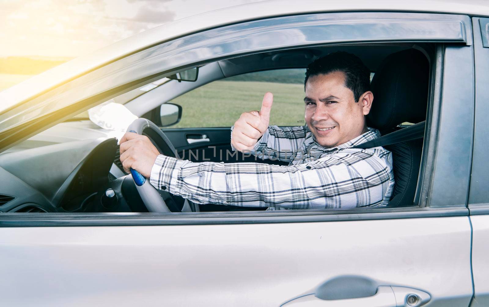 Portrait of a man showing thumbs up while driving, Man in his car giving a thumbs up, happy man in his car giving a thumbs up