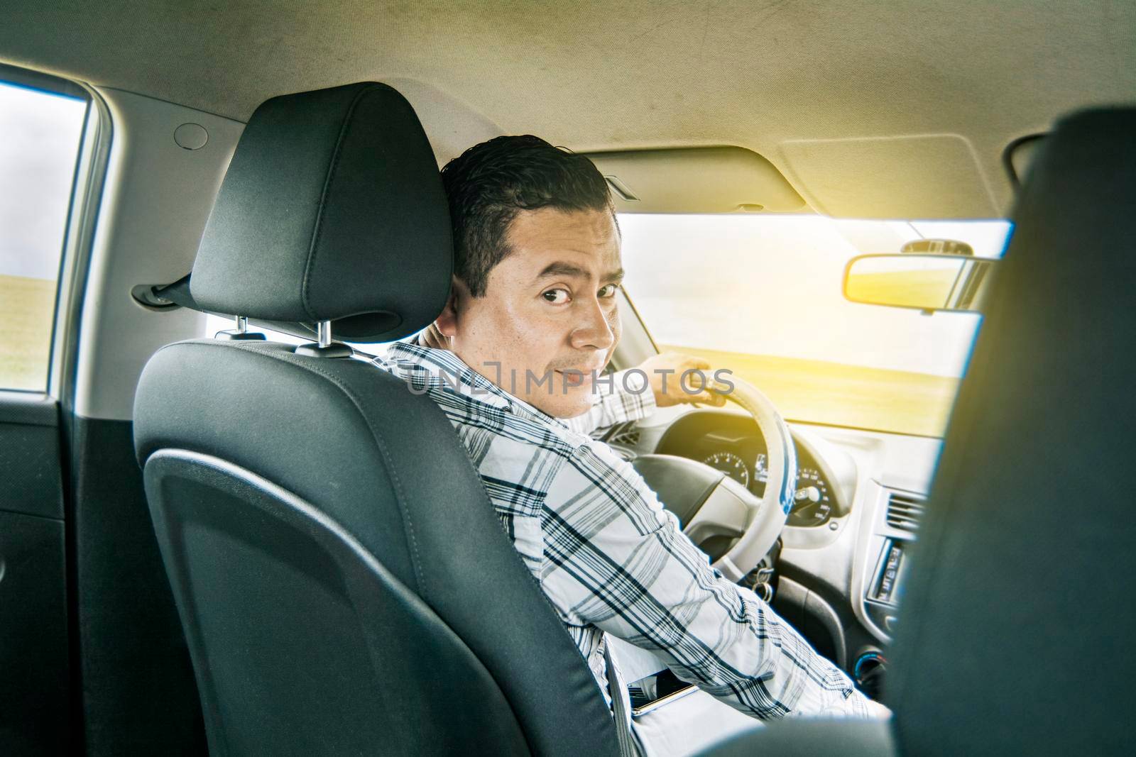 Happy young driver behind the wheel of a car. rear view of a smiling man behind the wheel, rear view of a smiling person sitting behind the wheel, Concept buying a car