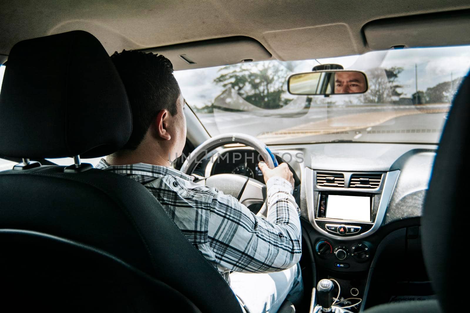 Back view of a man driving a car, Man's hands on the wheel of the car, inside view of a man driving a car, Concept of hands on the wheel of a car