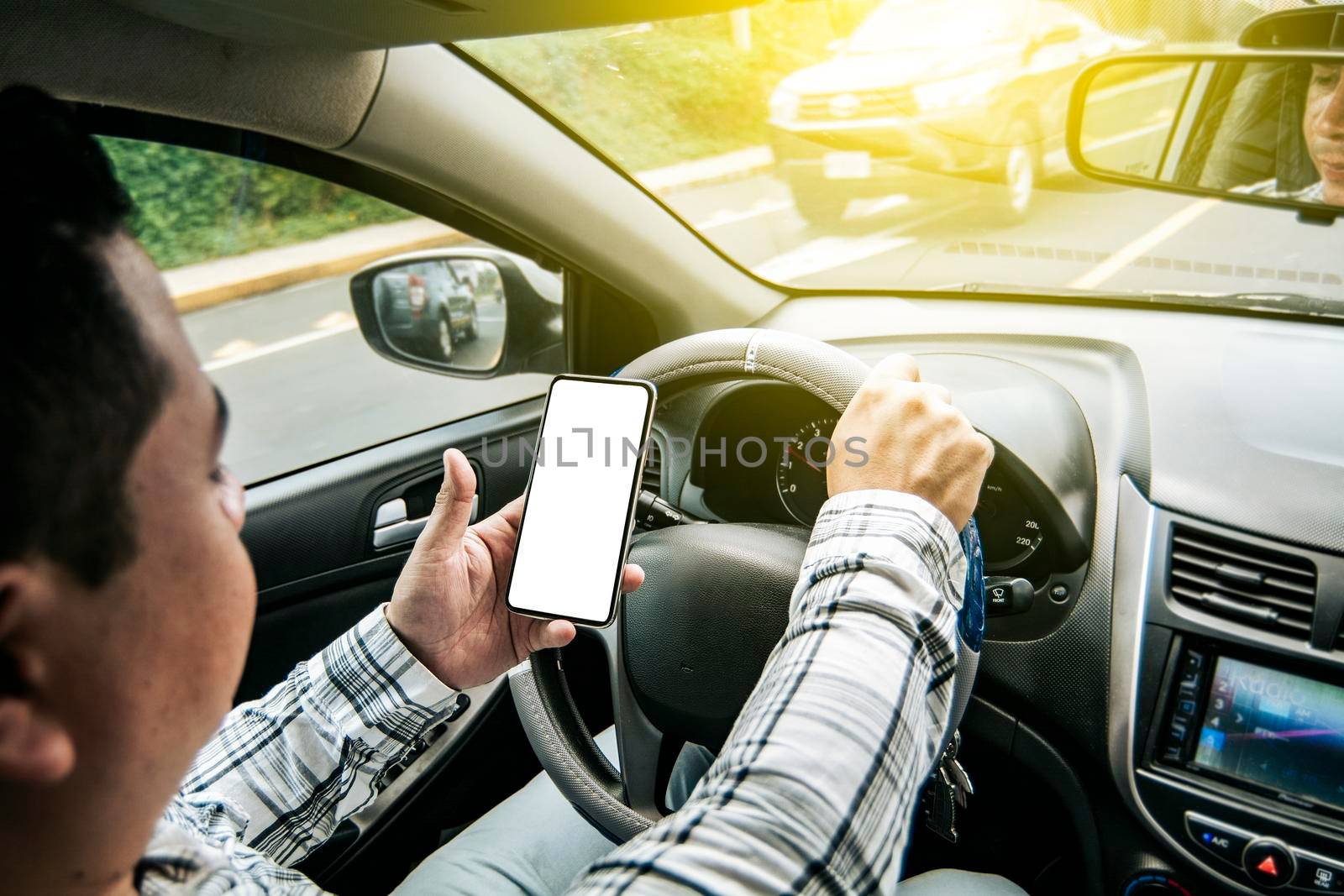 Distracted driver using the cell phone while driving, Man using his phone while driving, Person holding the cell phone and with the other hand the steering wheel, Concept of irresponsible driving