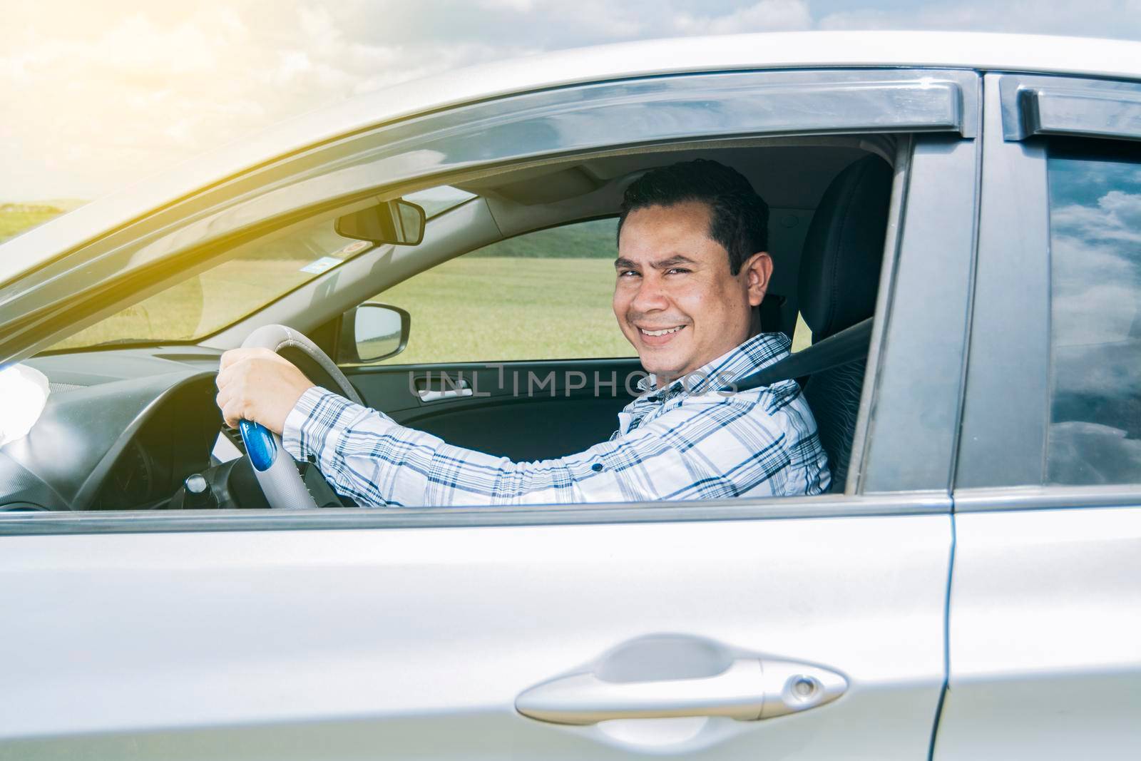 man smiling at the camera in his car, man smiling happily in his car, image of a person smiling and happy driving a car and looking at the camera