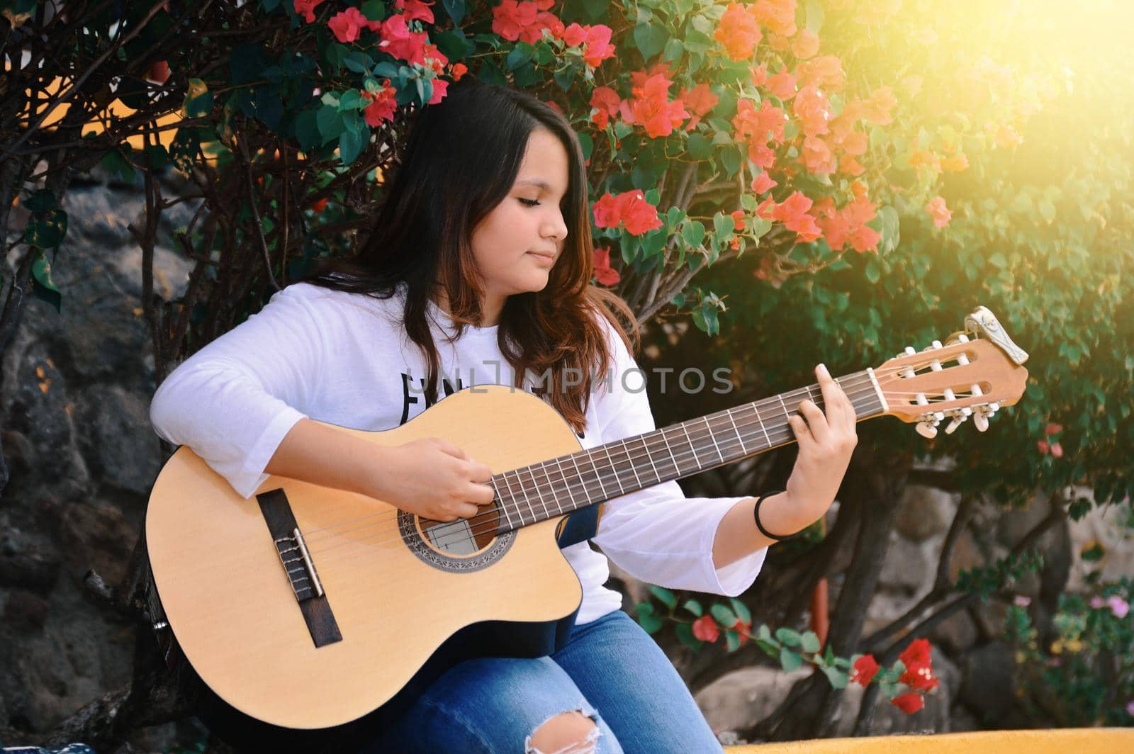 Portrait of a smiling girl playing guitar, A girl sitting playing guitar outdoors, Lifestyle of a girl playing guitar outdoors