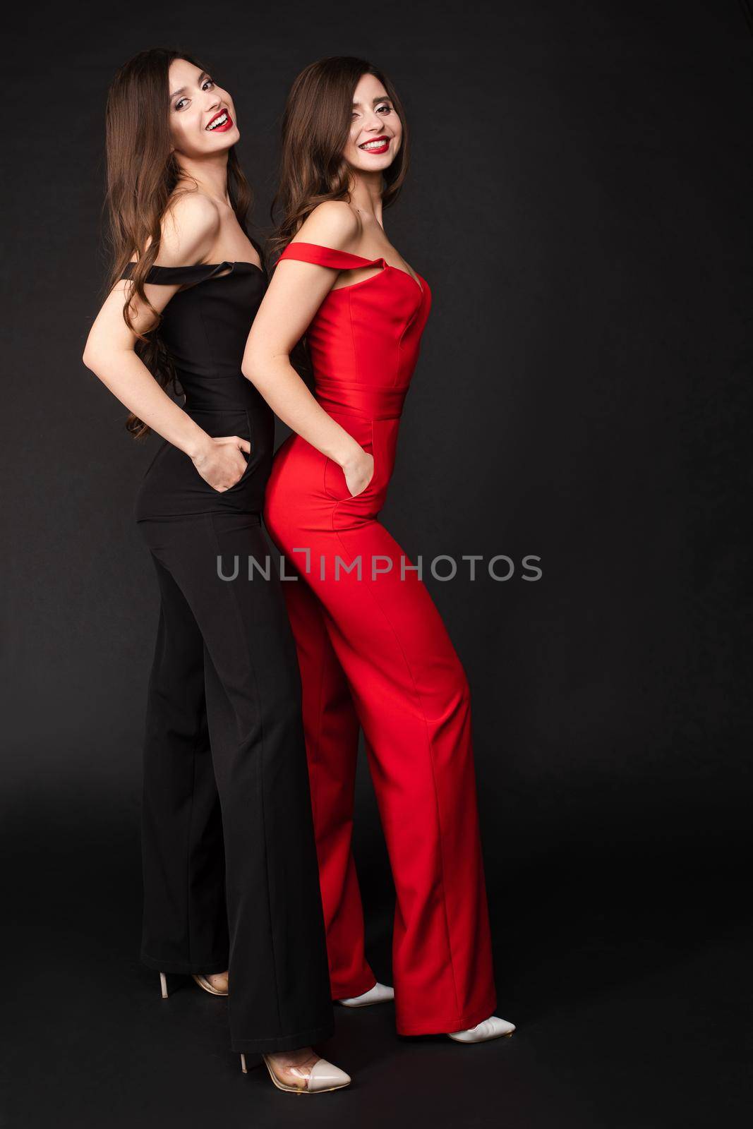 Young twins wearing similar black and red outfits and posing by StudioLucky