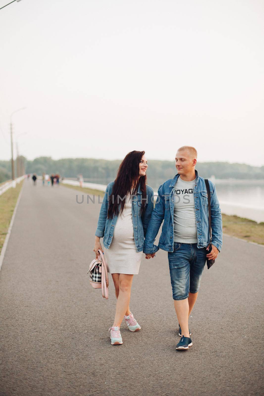 Future parent walking together in fresh air and laughing by StudioLucky