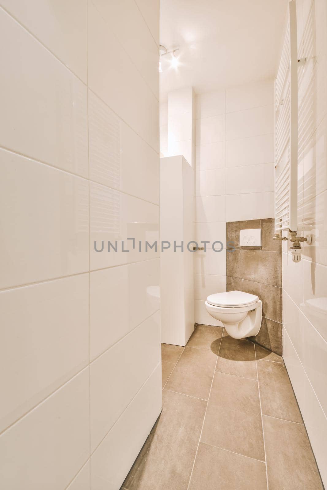 Wall hung toilet and small sink in corner in lavatory room with beige tile