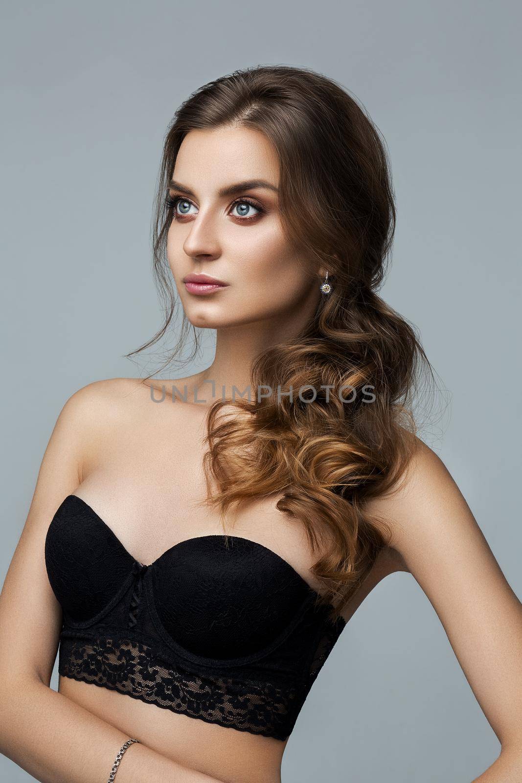 Studio fashion portrait of attractive sensual young woman with long wavy fair hair and blue eyes looking at camera. Natural beauty concept. Caucasian.