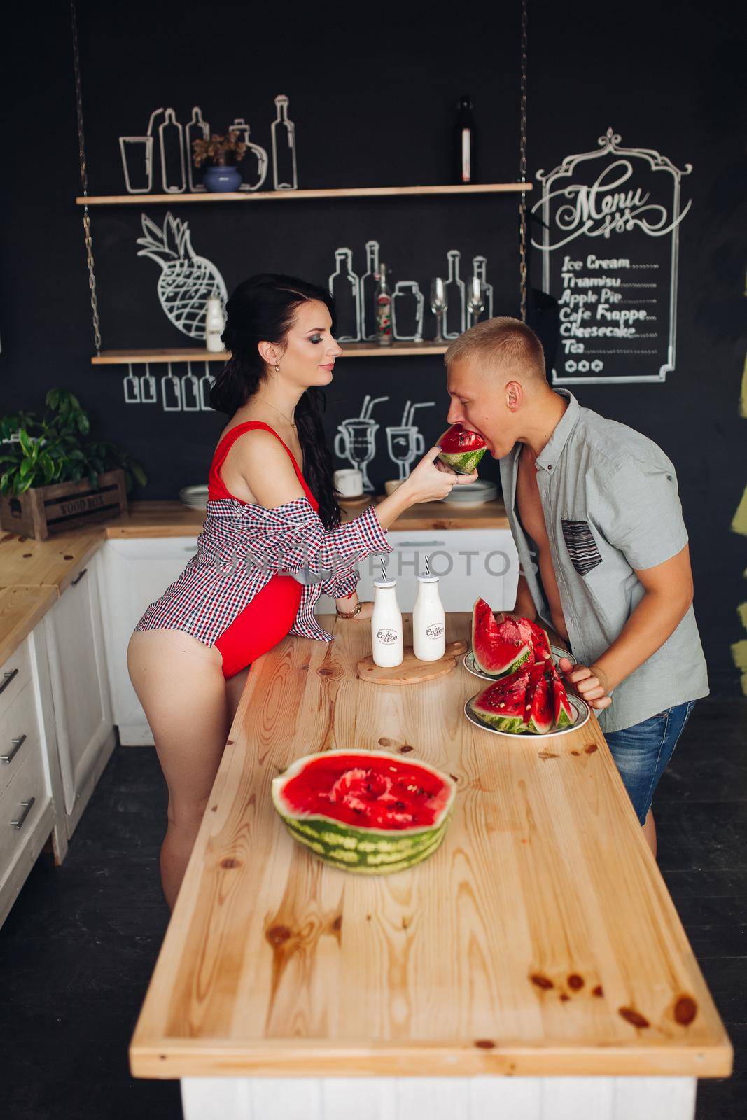 Side view of couple standing in kitchen and sharing meal. by StudioLucky