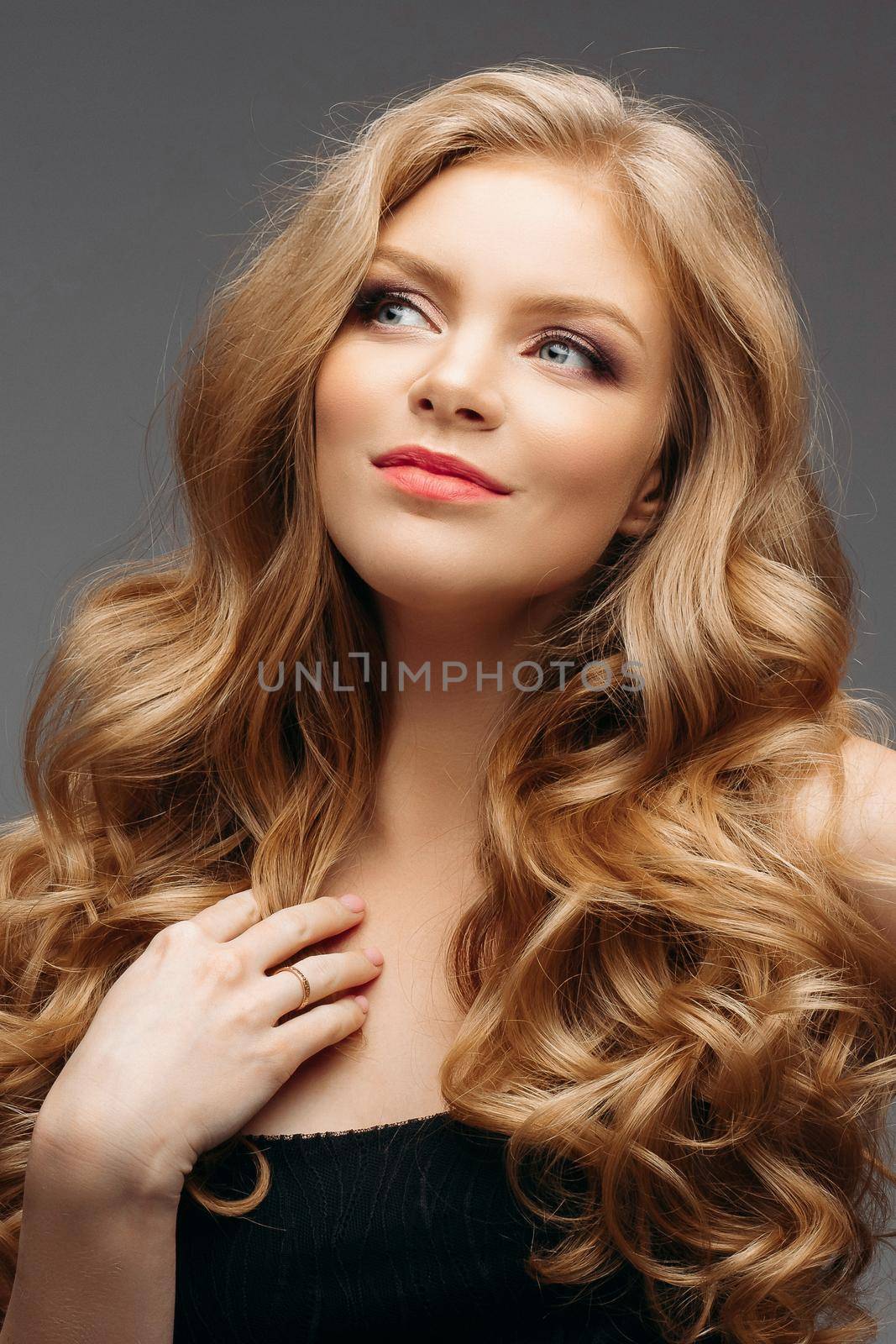 Studio fashion portrait of attractive sensual young woman with long wavy fair hair and blue eyes looking at camera. Natural beauty concept. Caucasian.