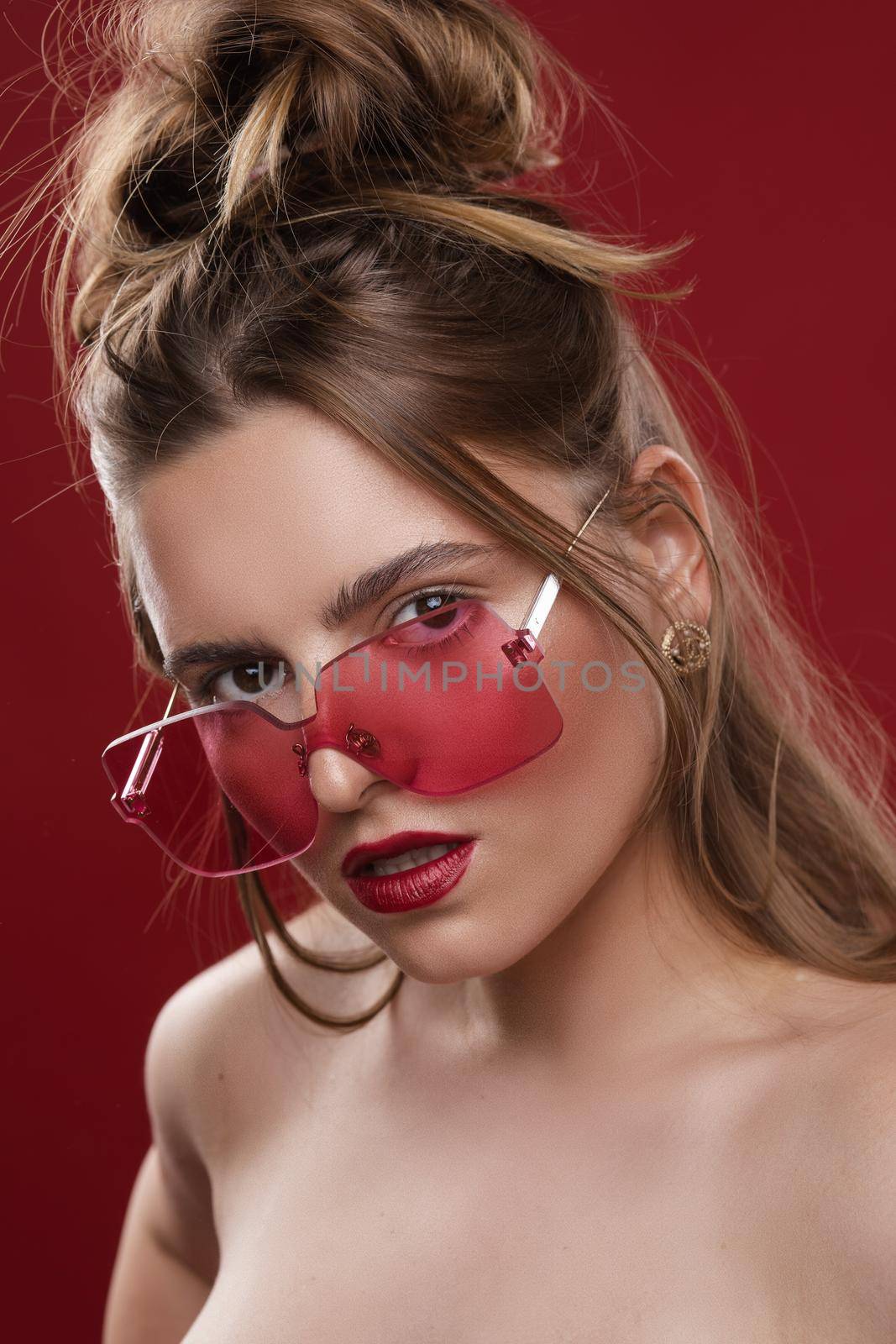 Gorgeous fashionable girl in pink sunglasses on red background. by StudioLucky