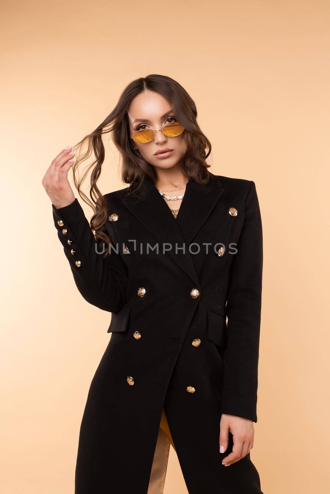 Confident sexy woman in coat and glasses looking at camera by StudioLucky