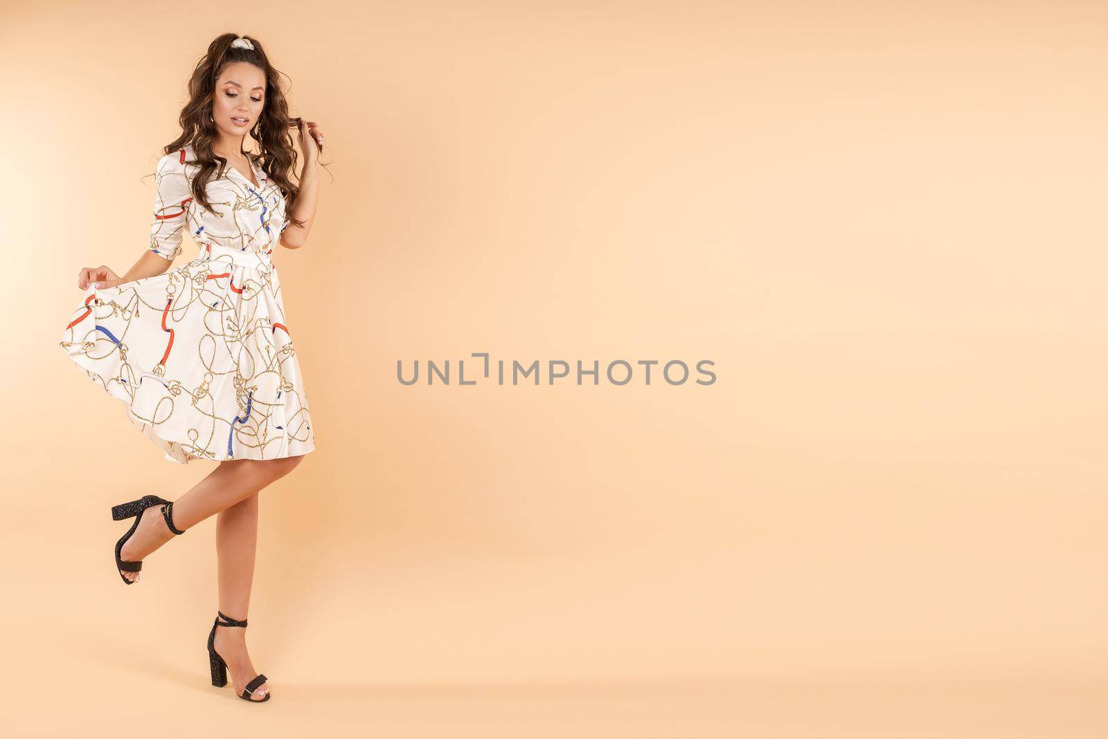 Front view of stylish girl wearing white light dress looking at camera and posing on isolated background. Pretty young woman with makeup and hairstyle enjoying new outfit. Concept of fashion.