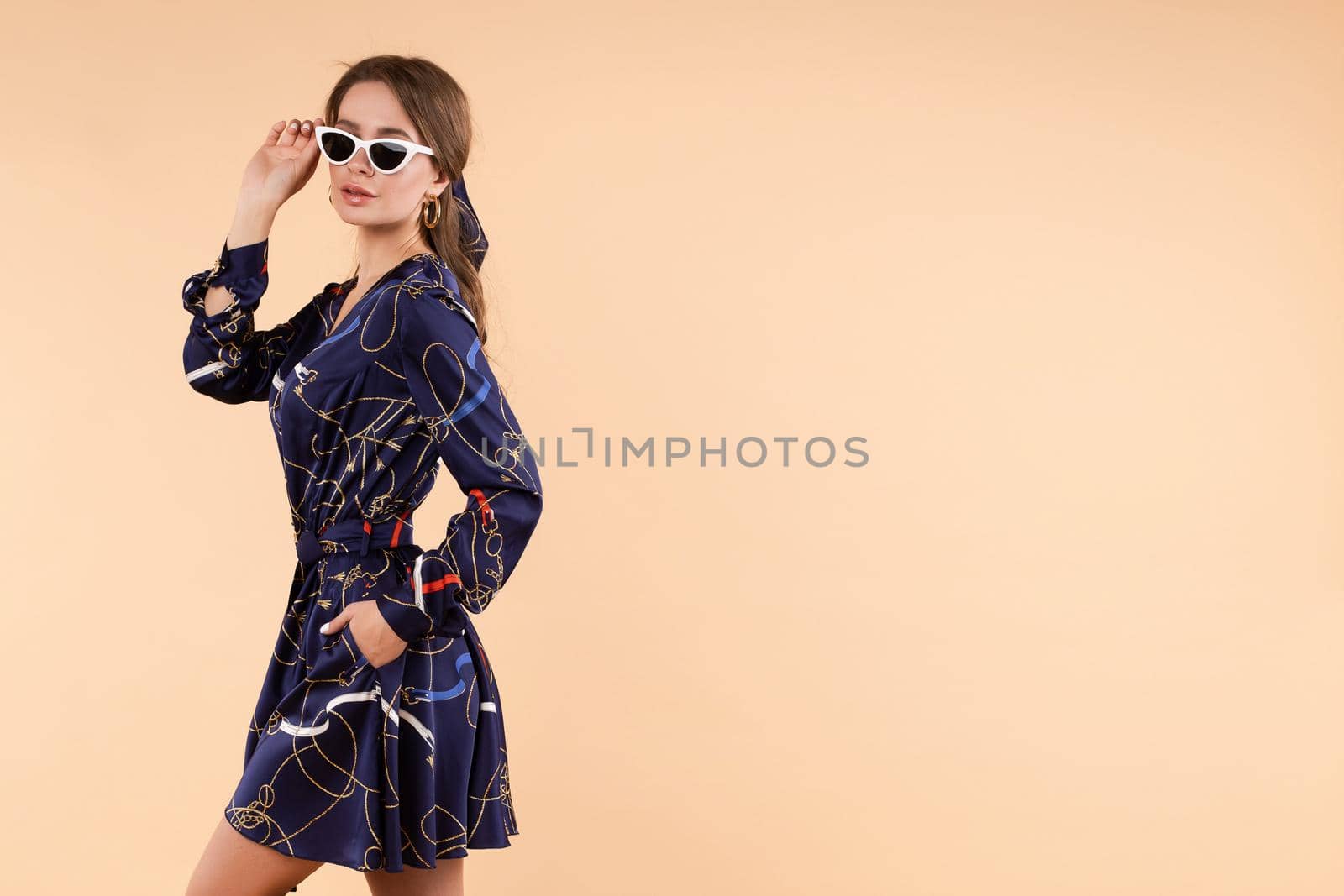 Stylish woman in blue dress and glasses posing in studio by StudioLucky