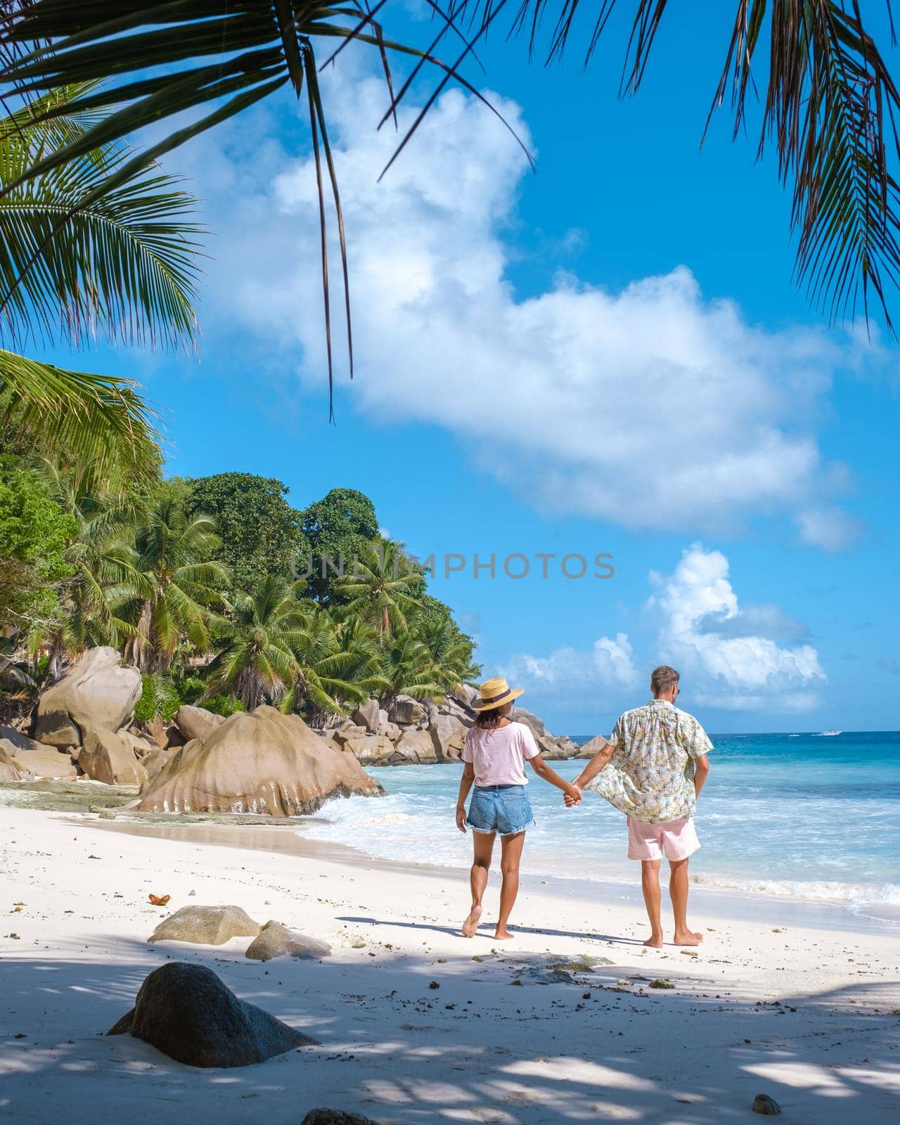 Anse Patates, La Digue Seychelles, young couple men and woman on a tropical beach during a luxury vacation in the Seychelles. Tropical beach Anse Patates, La Digue Seychelles by fokkebok