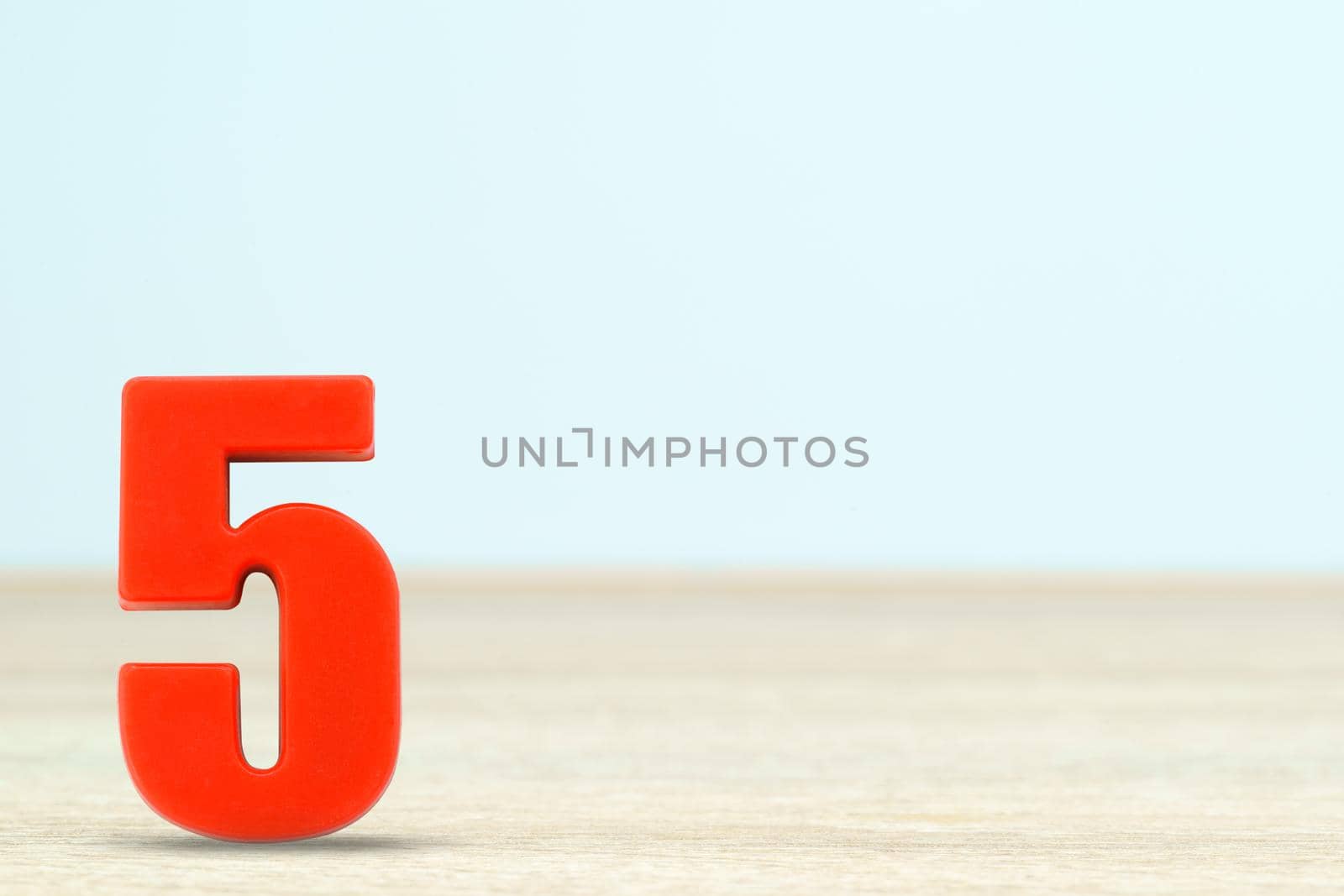 Shot of a number five made of red plastic on table with copy space