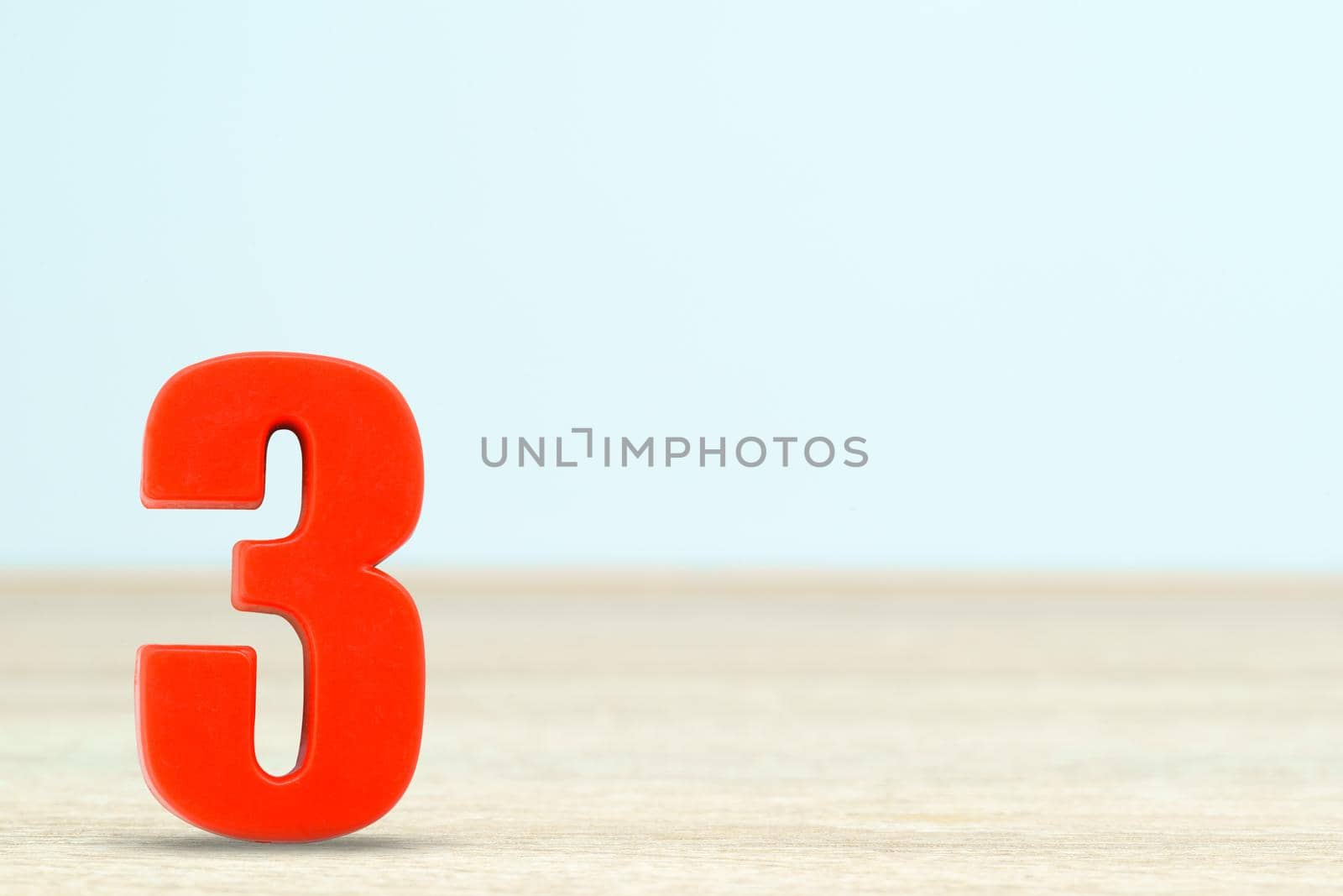 Shot of a number three made of red plastic on table with copy space