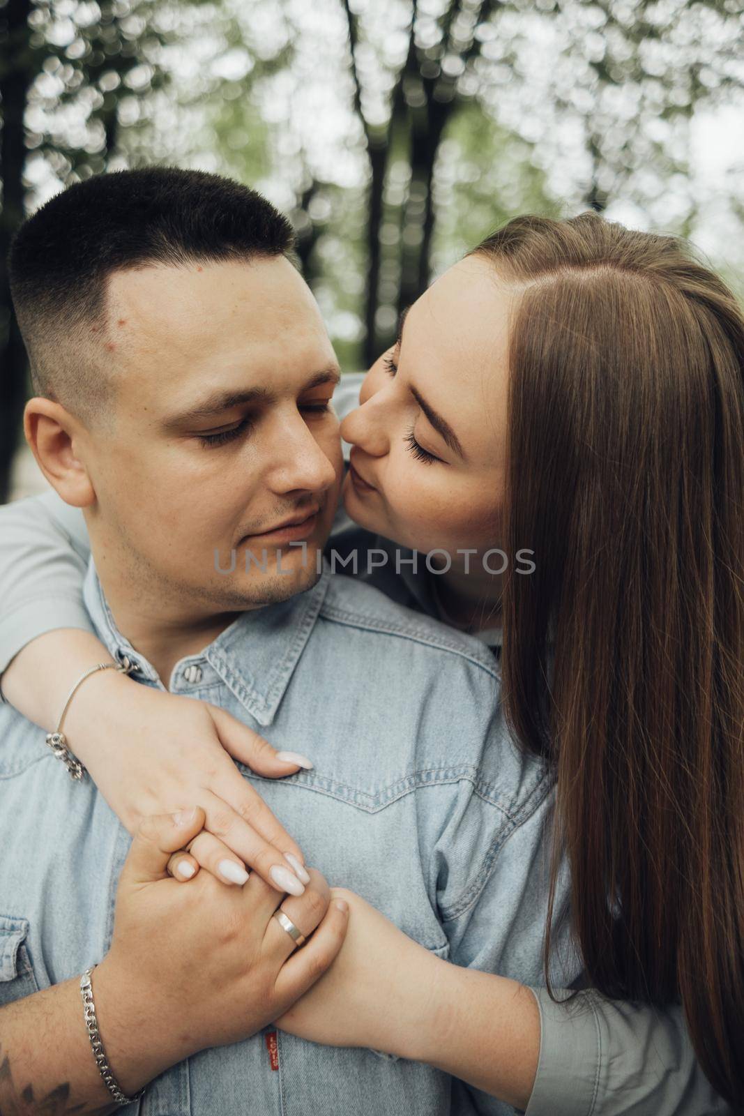 a girl hugs her boyfriend from behind and kisses her cheek by Symonenko