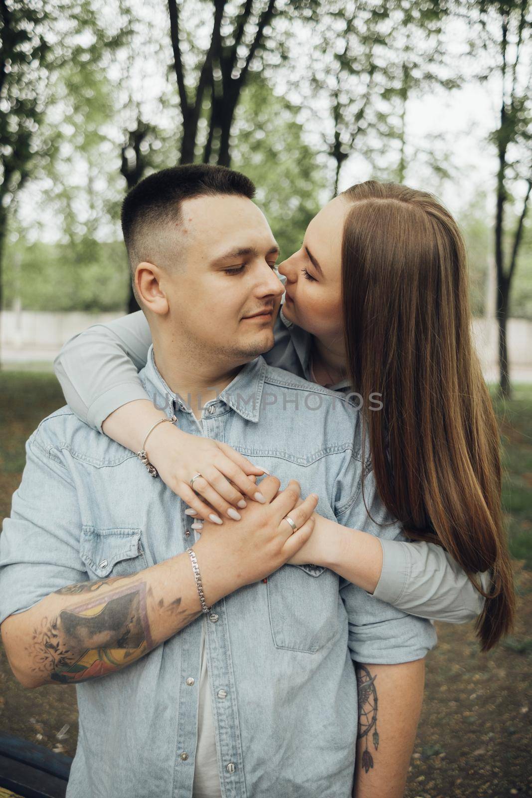 a girl hugs her boyfriend from behind and kisses her cheek by Symonenko