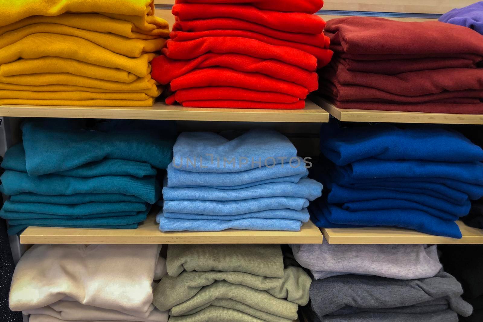 Rows of folded colorful clothes in a store