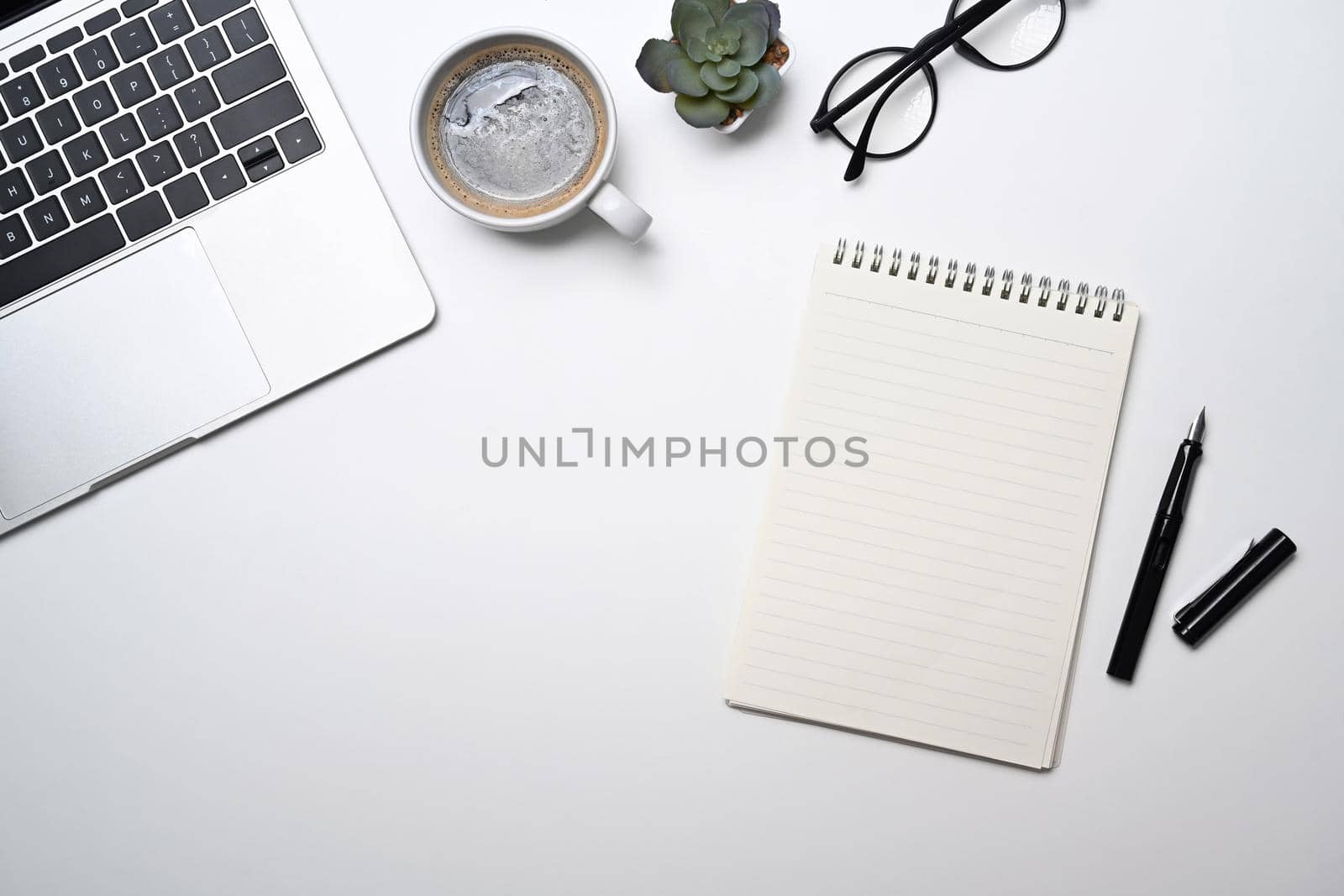 Blank notepad, glasses, coffee cup and laptop computer on white background. Top view.