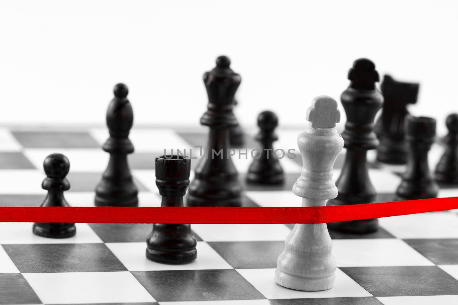 Chess leadership concept with King's figure crossing the red finish ribbon. Black and white tone