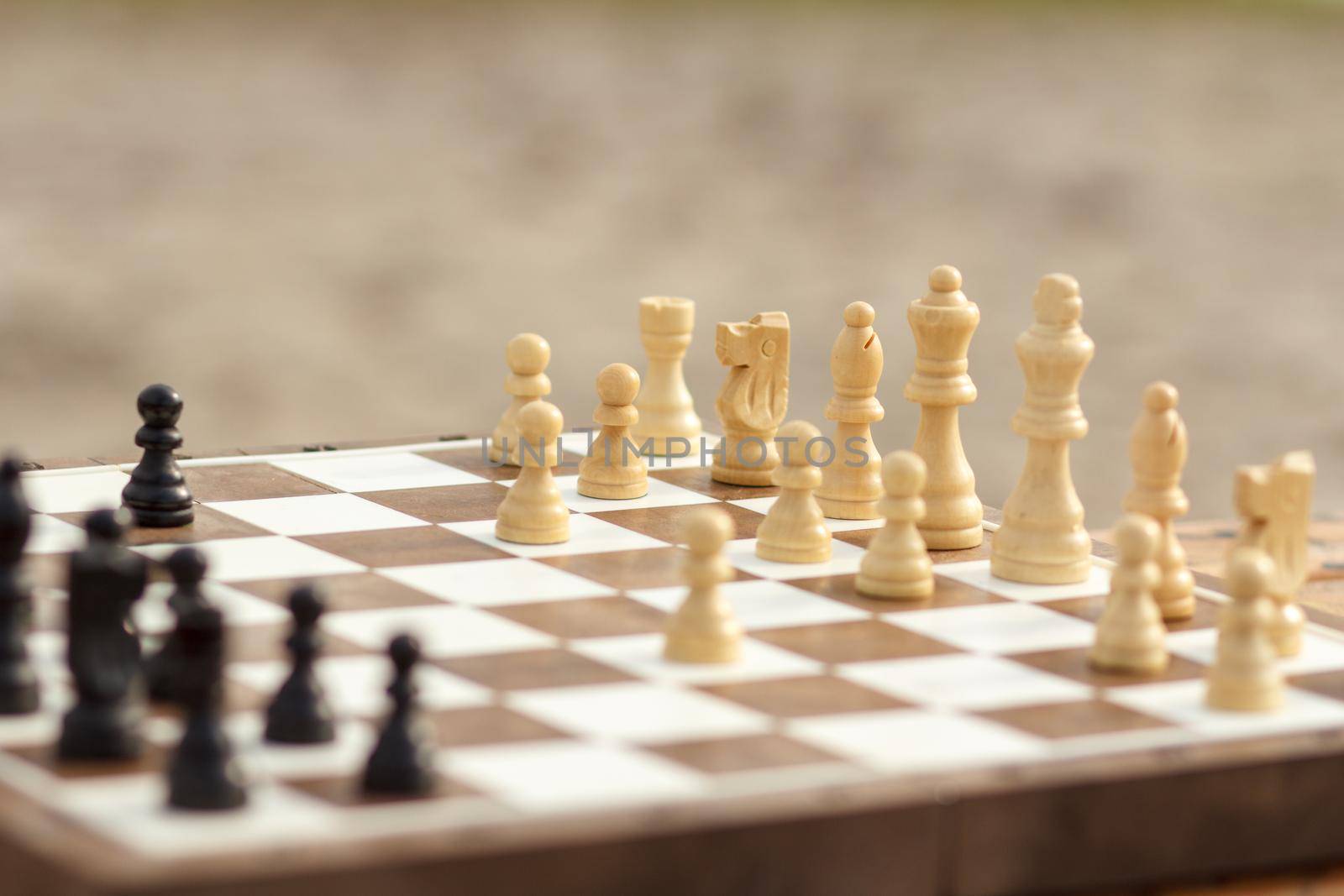 Close up chess pieces on board, selective focus on white pieces. Outdoors chess game