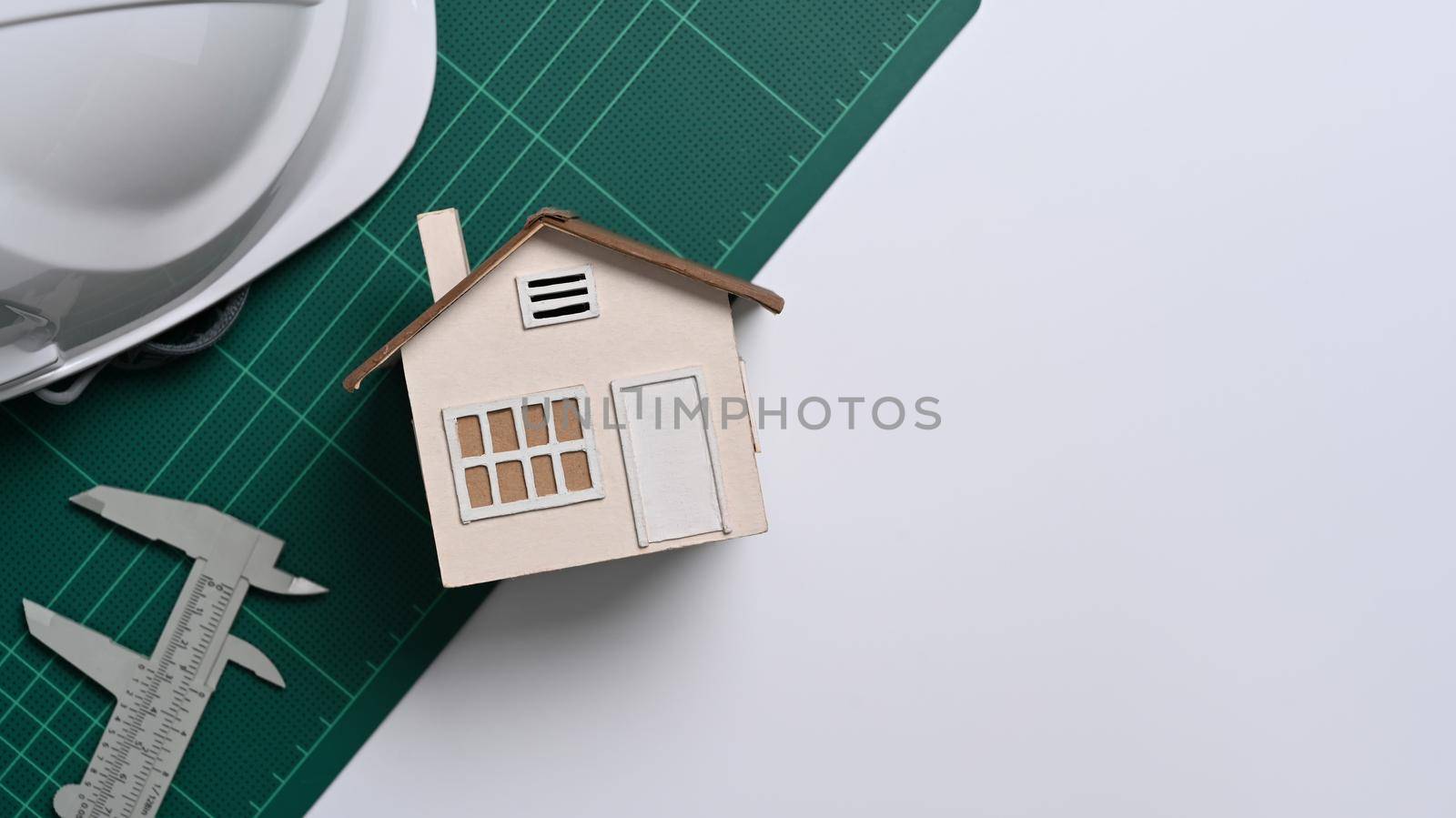 White plastic helmet and vernier caliper on office desk. Construction worker tools concept.