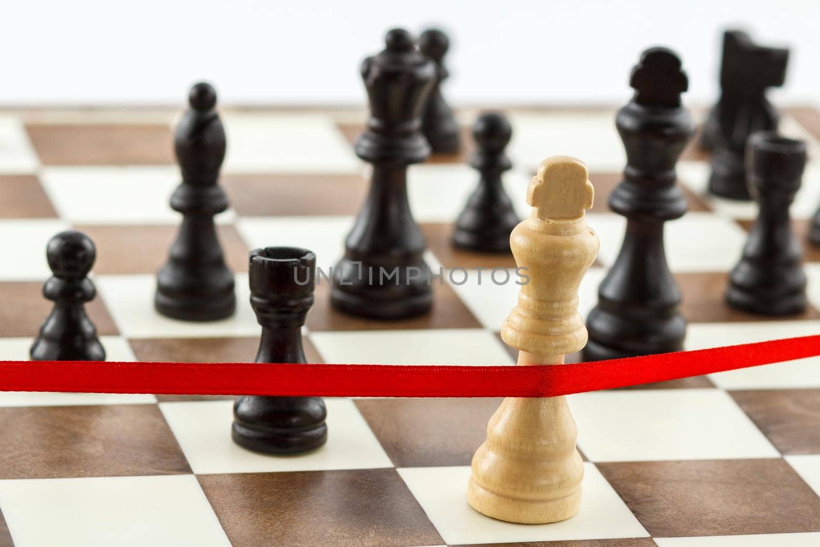 Business concept - strategy, competition, leadership, challenge. The King's figure is crossing the red finish ribbon