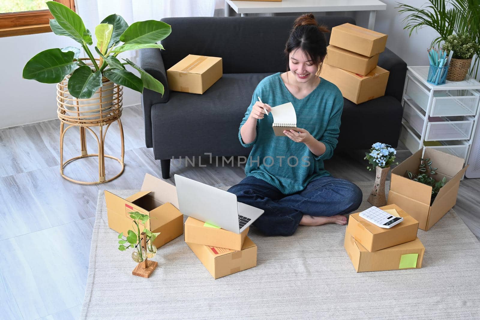 Young start up small business entrepreneur sitting in her home office and preparing parcel boxes for delivery.
