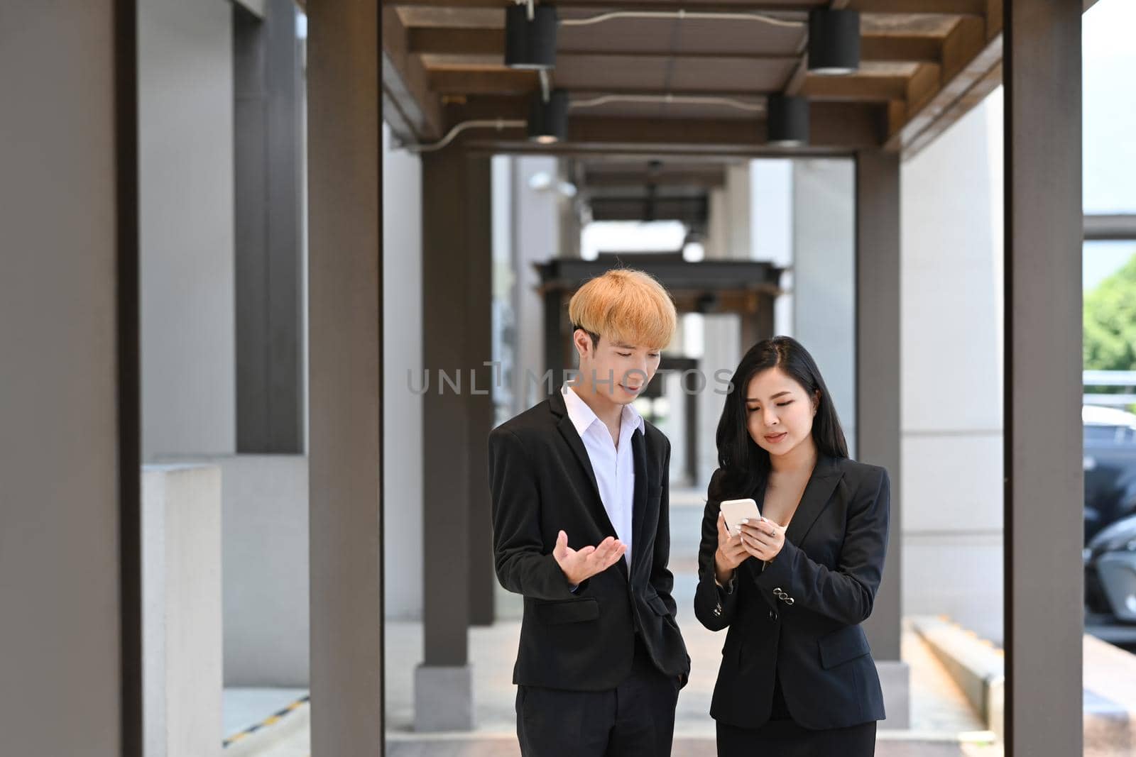 Young businesspeople in suit having a discussion while walking at modern office district.