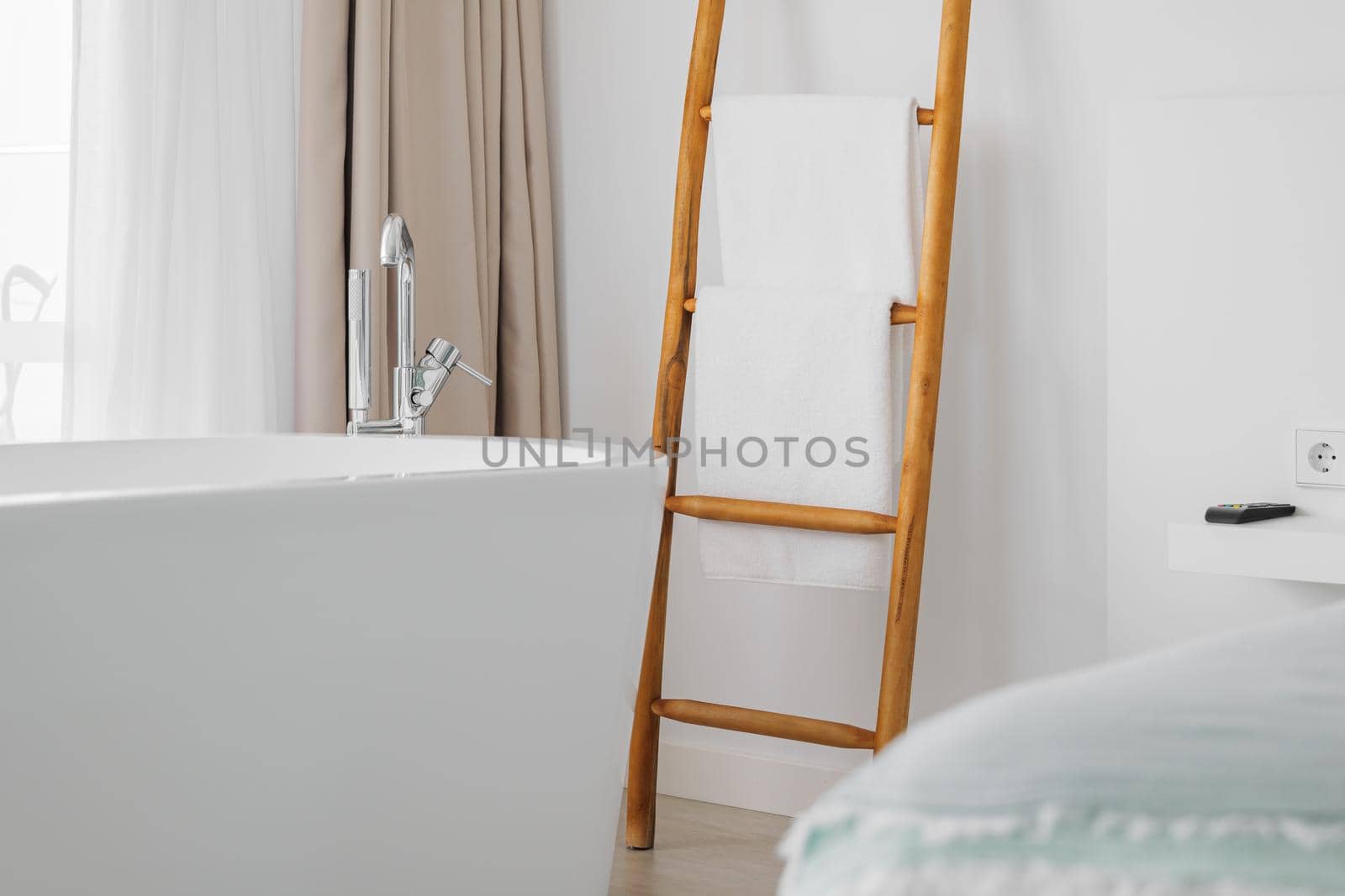 Modern hotel bedroom interior with bathroom, metal faucet and white towels on a decorative wooden staircase