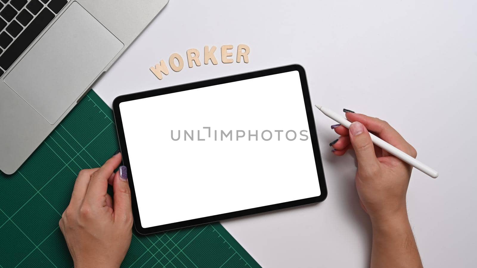 Female office worker holding stylus pen and writing on digital tablet. Above view.