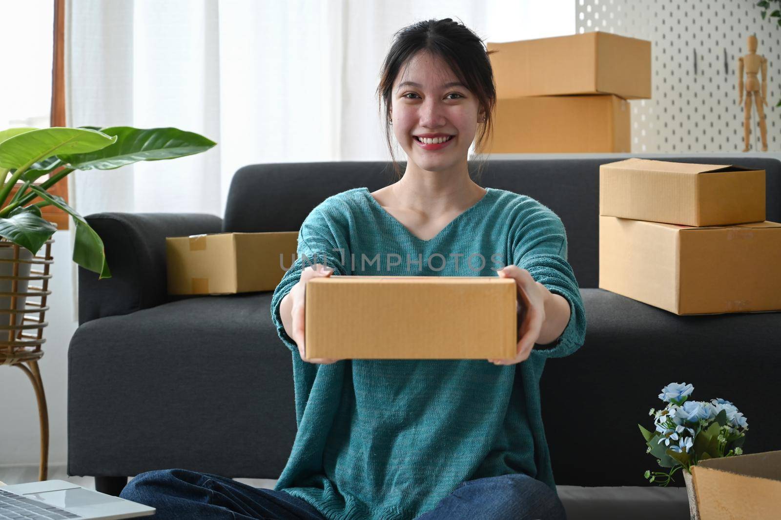 Startup small business entrepreneur holding parcel boxes of product and smiling to camera. E-commerce, Online selling concept.