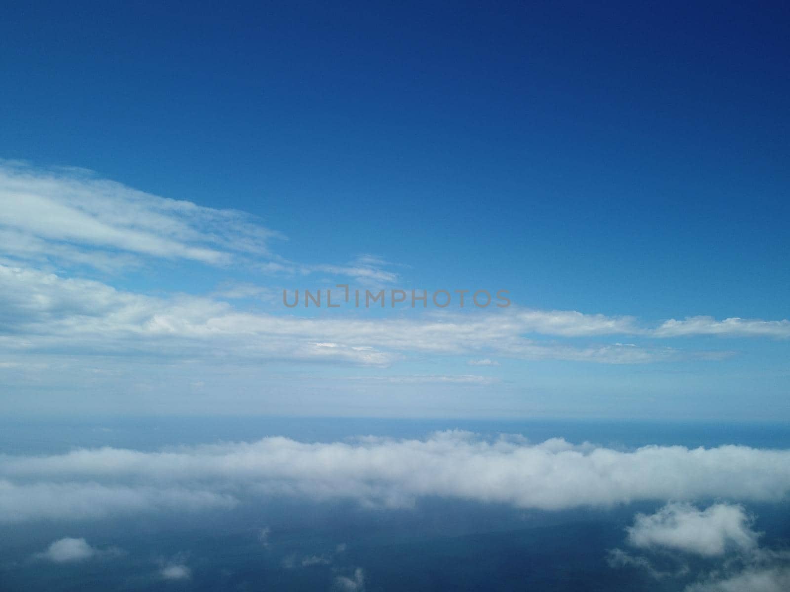 Aerial view. Blue sky sun and fog over calm sea. The drone flies over foggy and fluffy clouds. Abstract aerial nature summer ocean sunset sea and sky background. Vacation, travel and holiday concept. by panophotograph
