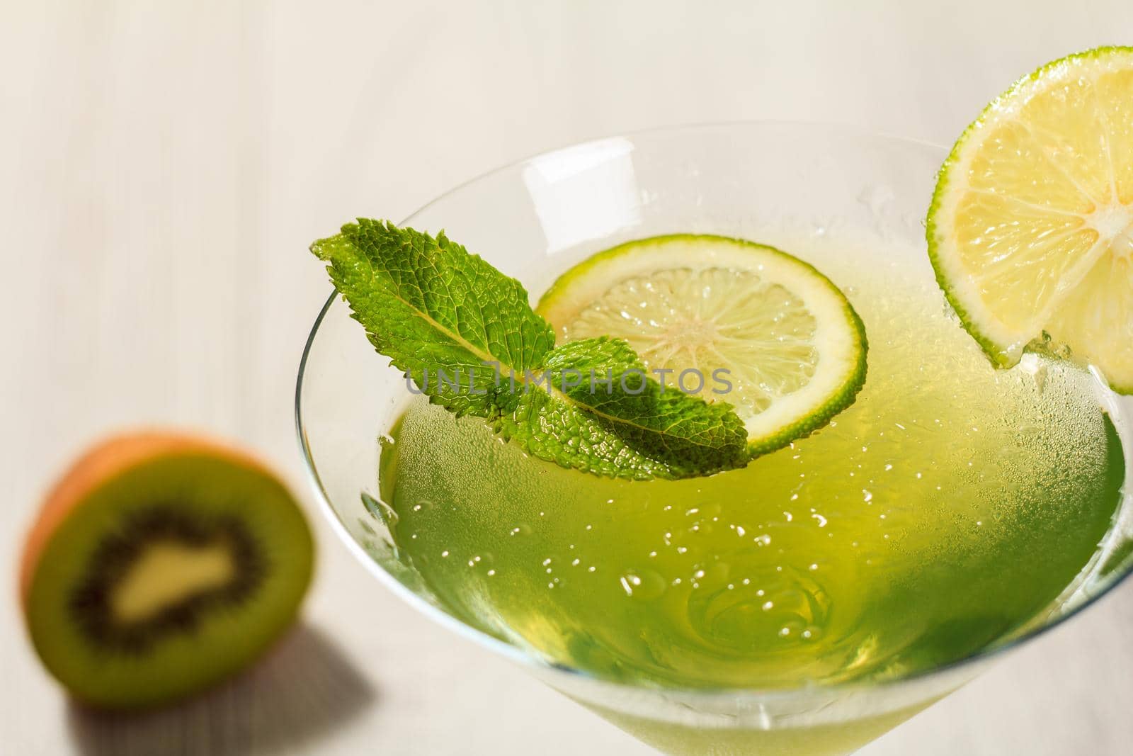 Kiwi jelly with lime pieces in the glass topped mint leaves Close up selective focus