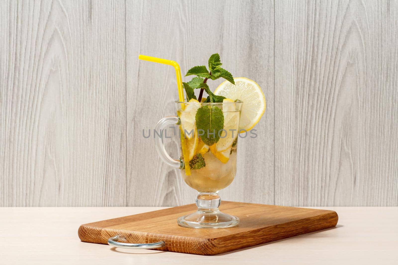 Carbonated lemonade with lemon slices and mint on an wooden cutting board, Cold beverage for hot summer day