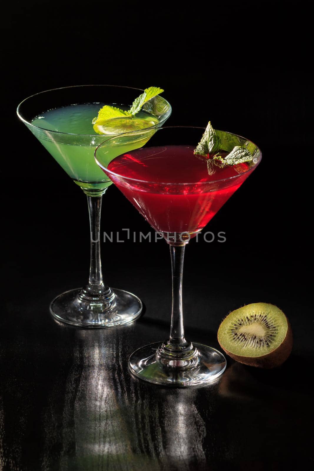 Kiwi and cherry jelly with lime pieces in the glasses topped mint leaves on the black background