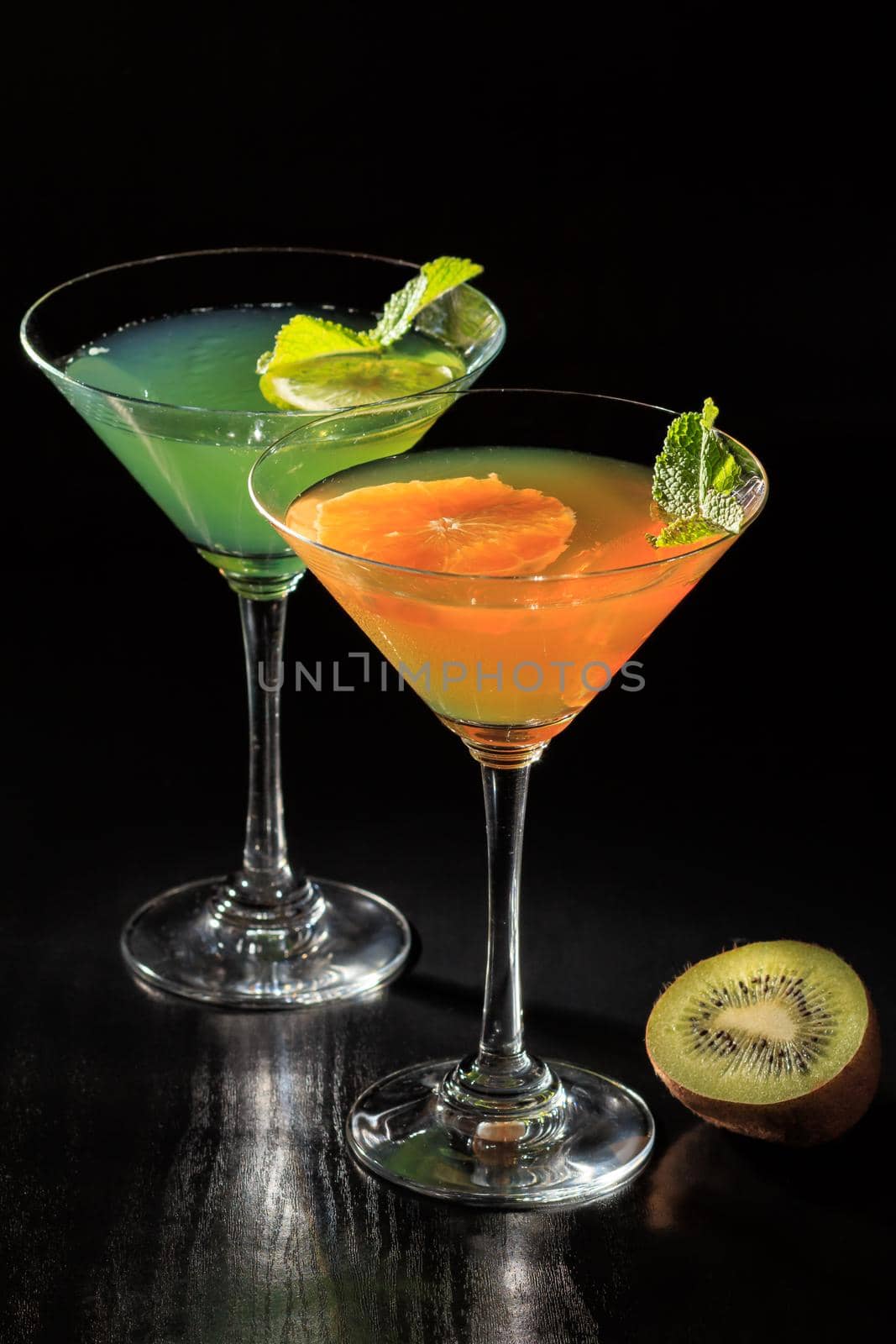 Kiwi and orange jelly with lime pieces in the glasses topped mint leaves on the black background