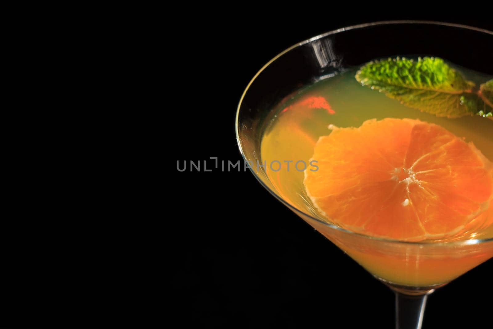 Kiwi jelly with lime pieces in the glass topped mint leaves in the black background