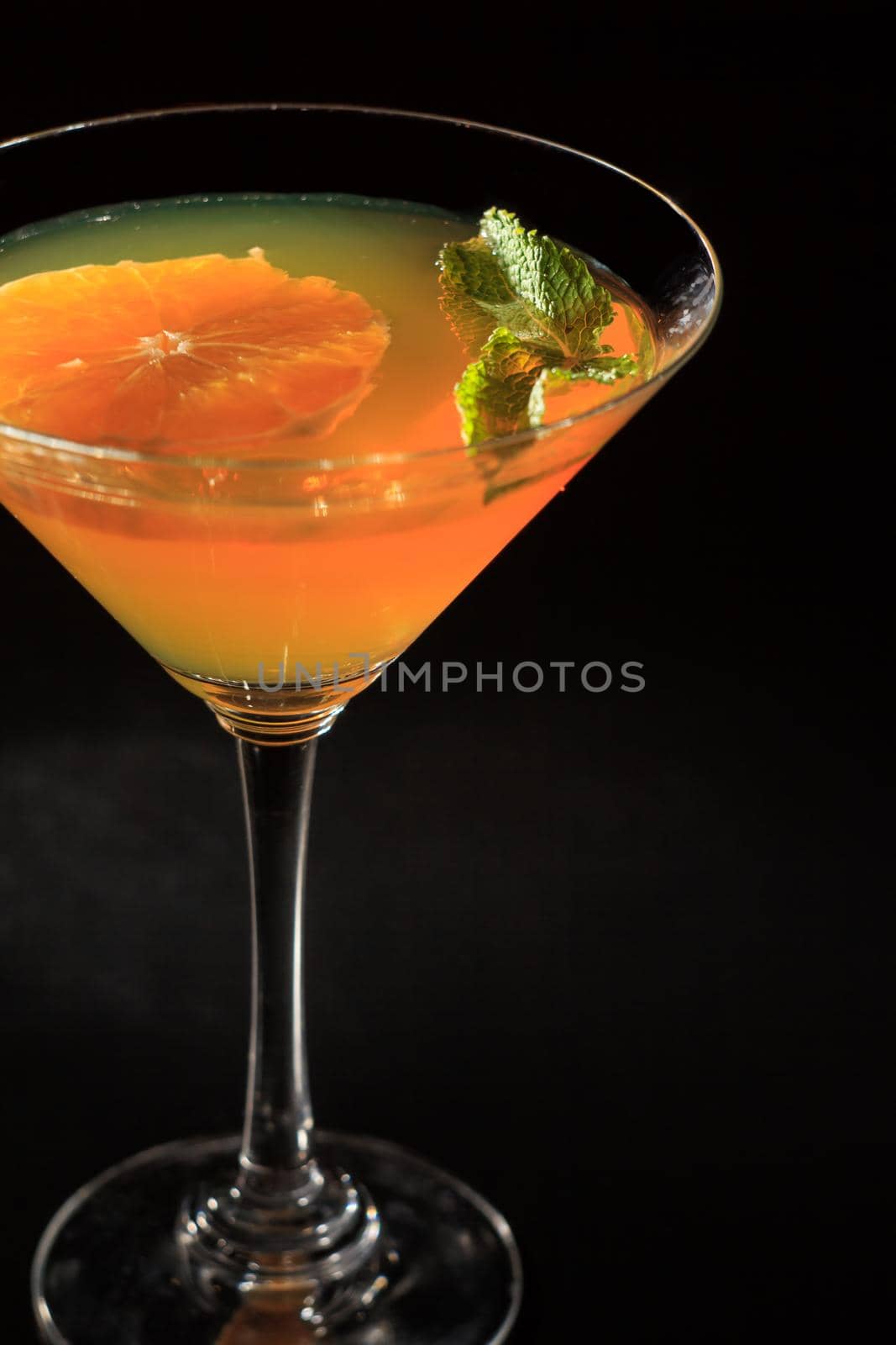 Orange jelly with lime pieces in the glass topped mint leaves in the black background